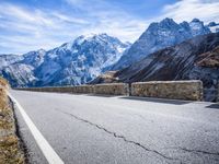 a man riding down the road on his bike past mountains in the background and clouds overhead