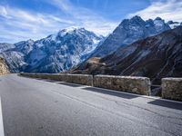 a man riding down the road on his bike past mountains in the background and clouds overhead