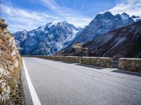 a man riding down the road on his bike past mountains in the background and clouds overhead