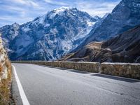 a man riding down the road on his bike past mountains in the background and clouds overhead