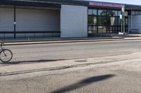 there is a man riding a bike near an empty building for eating and drinking tea