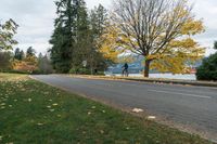 a bicyclist rides down a path in the middle of fall next to lake como