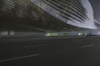 the city street is dark and empty of cars and buildings at night, as an illuminated sculpture stands in front of them