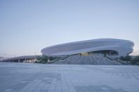 a walkway is paved with large steps outside a building made of concrete with curved design