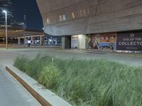 street view of an art museum lit up at night with lights on and posters in background