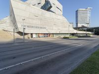 view of a modern building with a steeply shaped entrance in a large city, including a traffic light