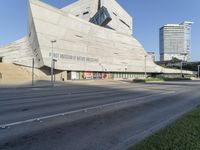 view of a modern building with a steeply shaped entrance in a large city, including a traffic light