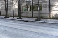 the empty sidewalk is next to tall buildings and a man walking down the street on his skate board