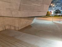 a skateboarder doing a jump off a ramp with a green hand rail on the sidewalk