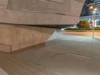 a skateboarder doing a jump off a ramp with a green hand rail on the sidewalk