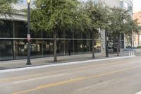 a man standing on the sidewalk of a street corner next to some trees and buildings