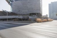 the sun casts a shadow on the street next to a building with a curved roof