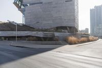 the sun casts a shadow on the street next to a building with a curved roof