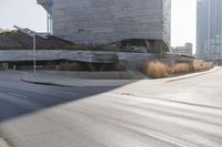 the sun casts a shadow on the street next to a building with a curved roof