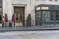 a person walking by a city street next to the building with its entrance open and there is a person walking out front of it