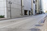 an empty street in front of buildings and tall building with multiple lamps and a bicycle rack