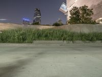 a red skateboarder doing a trick in a city setting at night time with tall grass