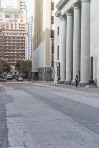 a guy on his skateboard goes down the street in city area with several tall buildings