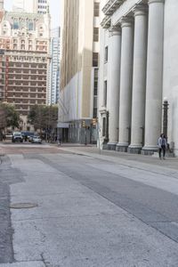 a guy on his skateboard goes down the street in city area with several tall buildings