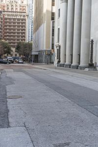 a guy on his skateboard goes down the street in city area with several tall buildings