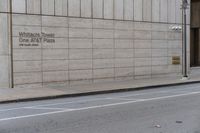 a tall cement building sitting behind an empty sidewalk, near a street and traffic light