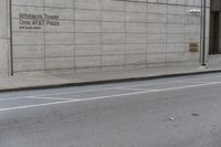 a tall cement building sitting behind an empty sidewalk, near a street and traffic light