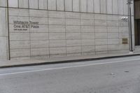 a tall cement building sitting behind an empty sidewalk, near a street and traffic light