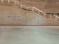 a metal staircase and sign in an empty parking garage area, including a ramp for cars to go up