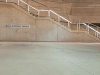 a metal staircase and sign in an empty parking garage area, including a ramp for cars to go up