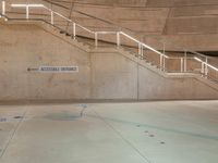 a metal staircase and sign in an empty parking garage area, including a ramp for cars to go up