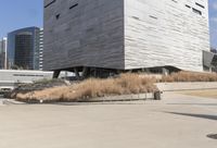 two people on skateboards on concrete outside of a building with tall buildings in the background