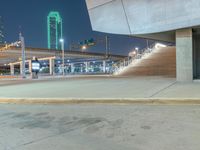 a fire hydrant sitting on the side of a road near some buildings at night