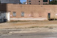 a street sign with signs on the building side of it and dirt next to the road