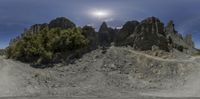 a very strange, dark rocky mountain landscape with rocks and trees in the foreground