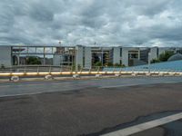 the sky is cloudy and dark over an empty street with two buildings in the back