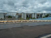 the sky is cloudy and dark over an empty street with two buildings in the back