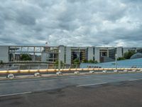 the sky is cloudy and dark over an empty street with two buildings in the back