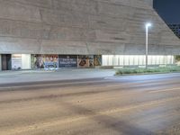 the street is dark as it appears in front of a building with signage on the side of it