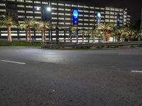 the empty street is dark with no cars on it as the building is lit up