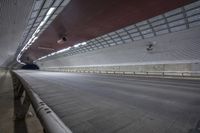 an empty street inside a high tunnel with a red roof above it and a black car