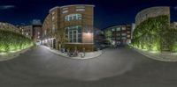 the image is panoramic of an intersection in a city with some street lights on