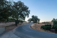 a winding, empty road going up the side of a hill on a clear day