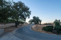 a winding, empty road going up the side of a hill on a clear day