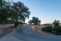 a winding, empty road going up the side of a hill on a clear day