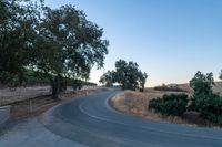 a winding, empty road going up the side of a hill on a clear day