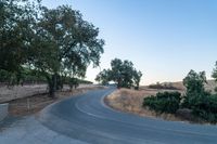 a winding, empty road going up the side of a hill on a clear day