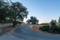 a winding, empty road going up the side of a hill on a clear day