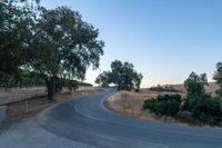 a winding, empty road going up the side of a hill on a clear day