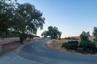 a winding, empty road going up the side of a hill on a clear day