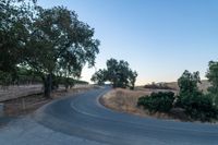 a winding, empty road going up the side of a hill on a clear day